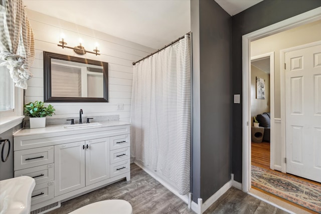 bathroom featuring visible vents, baseboards, wood finished floors, and vanity