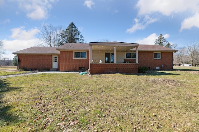 rear view of house featuring brick siding, crawl space, and a lawn