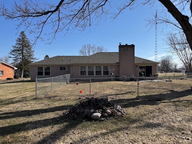 rear view of house with fence, a lawn, brick siding, and a chimney