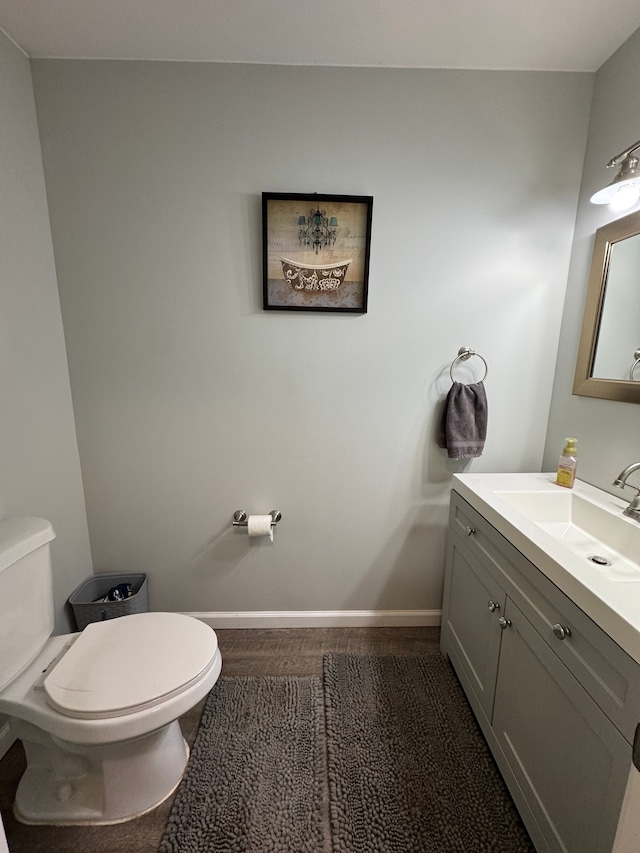 half bath with toilet, vanity, and baseboards