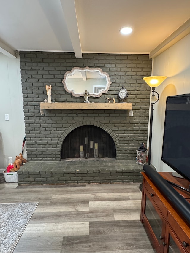 living area with beamed ceiling, a fireplace, and wood finished floors