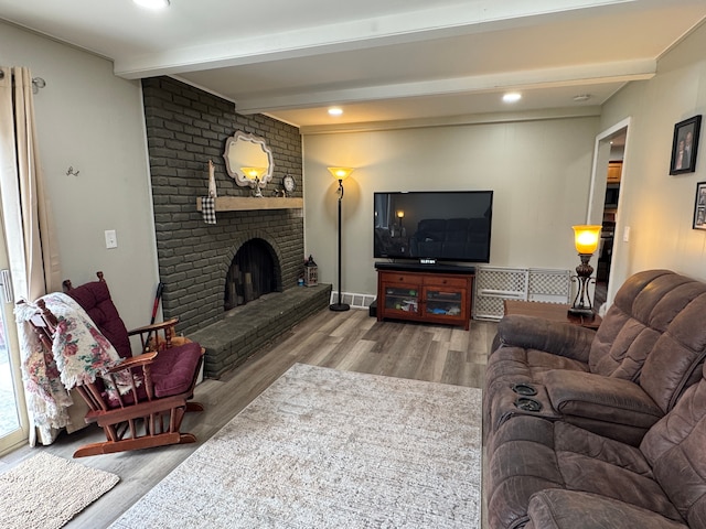 living room featuring recessed lighting, beamed ceiling, wood finished floors, and a fireplace