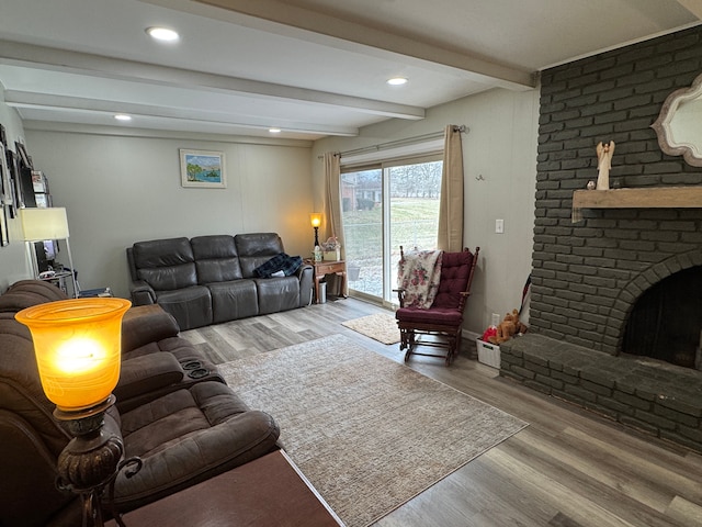 living room with beamed ceiling, recessed lighting, a brick fireplace, and wood finished floors