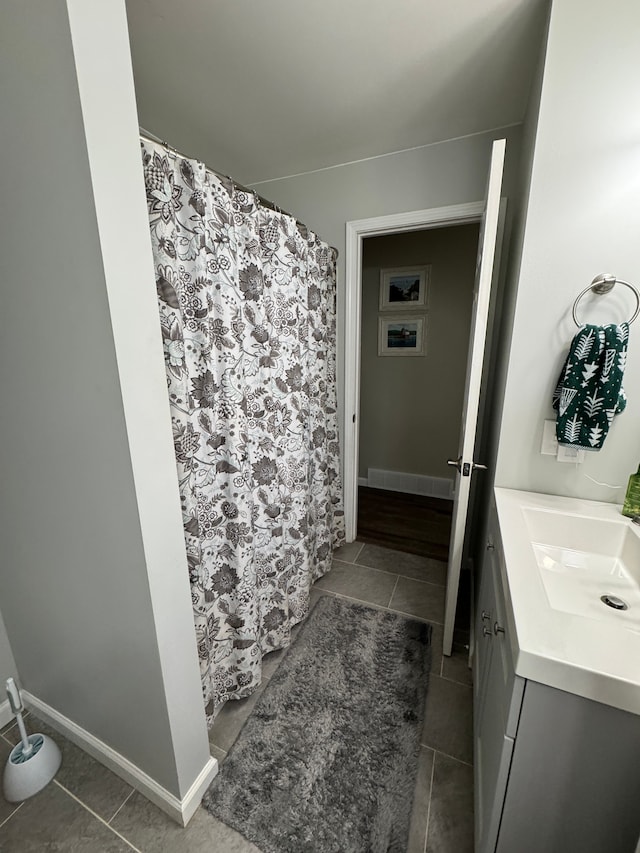 bathroom featuring a shower with shower curtain, baseboards, and vanity