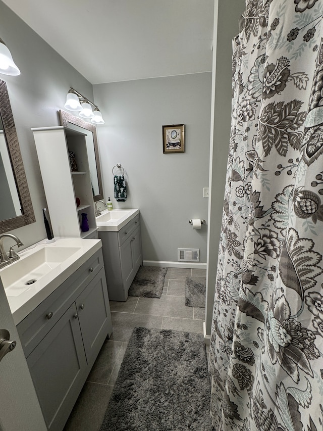 bathroom featuring visible vents, two vanities, baseboards, and a sink