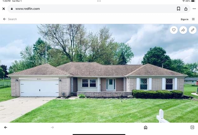 ranch-style home featuring an attached garage, concrete driveway, and a front yard