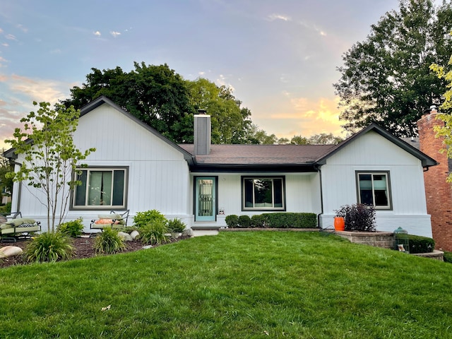 ranch-style house with a front yard, a chimney, and a shingled roof