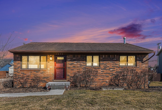 view of front of house featuring brick siding, a shingled roof, and a front yard