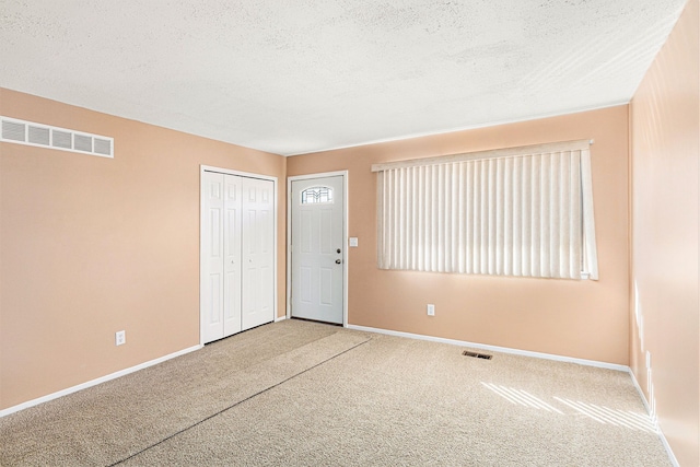 empty room featuring carpet, visible vents, and a textured ceiling