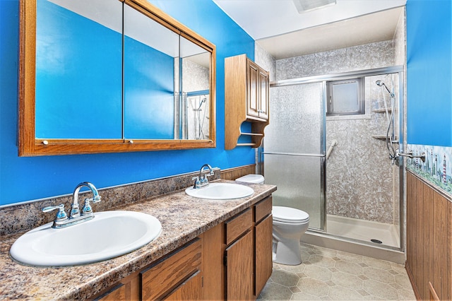 bathroom featuring double vanity, a shower stall, toilet, and a sink