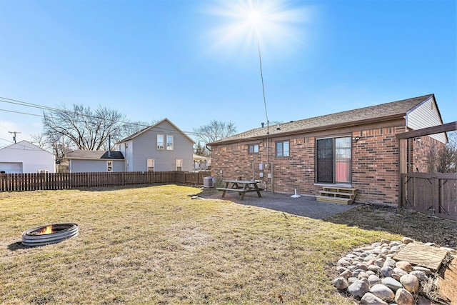 back of property featuring a yard, entry steps, an outdoor fire pit, and a fenced backyard