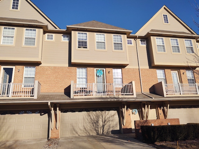 back of property featuring brick siding, an attached garage, and driveway