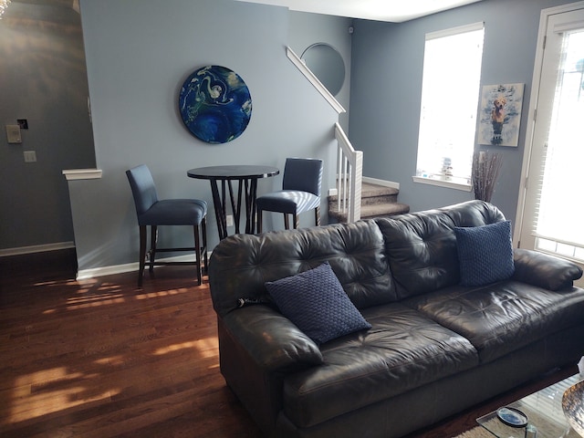 living area with dark wood-style floors, stairs, and baseboards