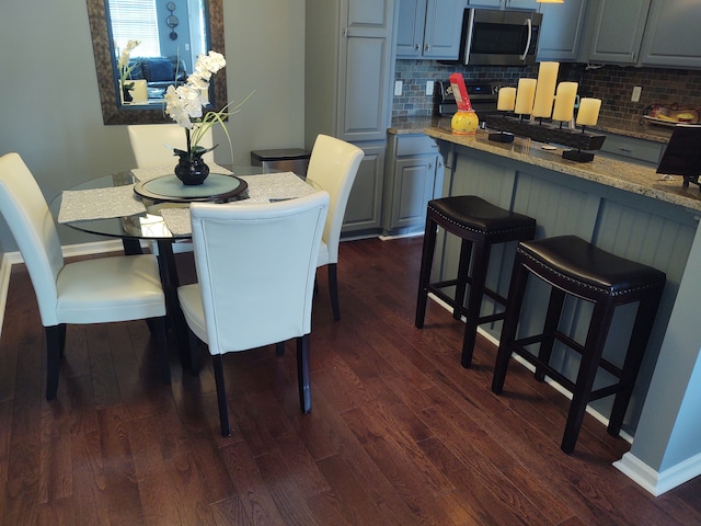 dining area with baseboards and dark wood-type flooring