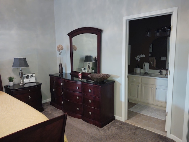 carpeted bedroom featuring baseboards, ensuite bathroom, and a sink