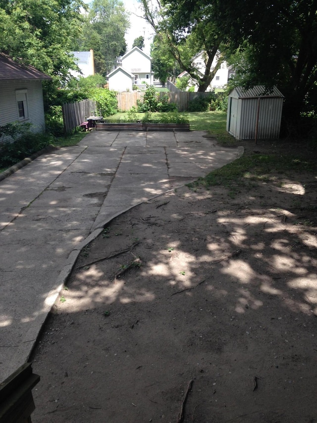 exterior space featuring an outbuilding, fence, a shed, and a patio area