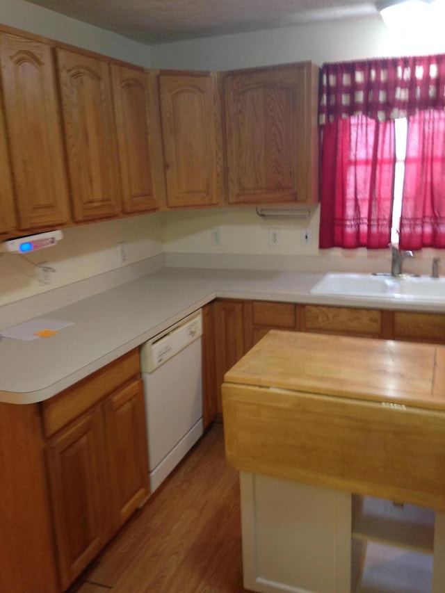 kitchen featuring a sink, dishwasher, and light wood finished floors