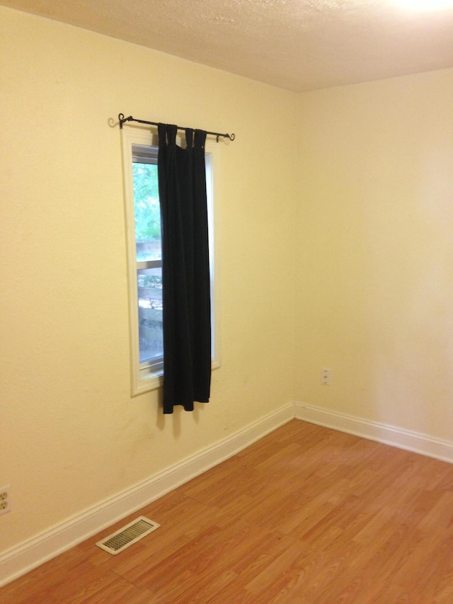 spare room with visible vents, light wood-style flooring, and baseboards