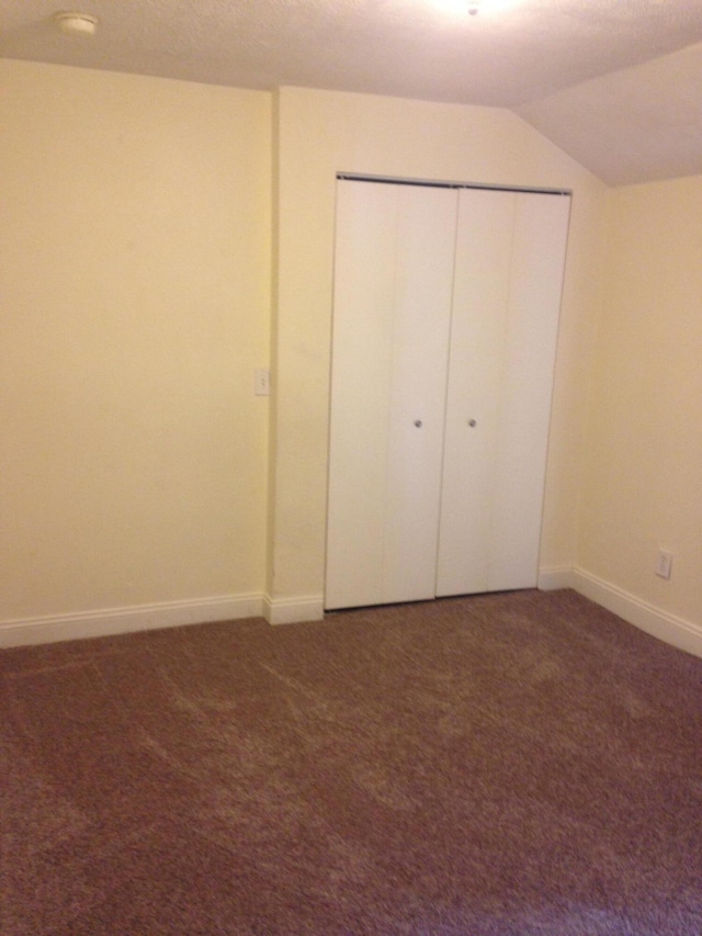 unfurnished bedroom with a closet, baseboards, carpet, and vaulted ceiling