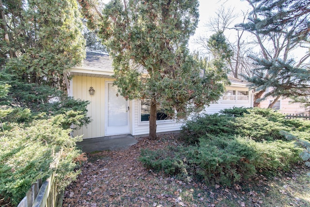 property entrance featuring a garage and a shingled roof