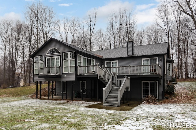 back of house featuring stairway, roof with shingles, a wooden deck, and a chimney