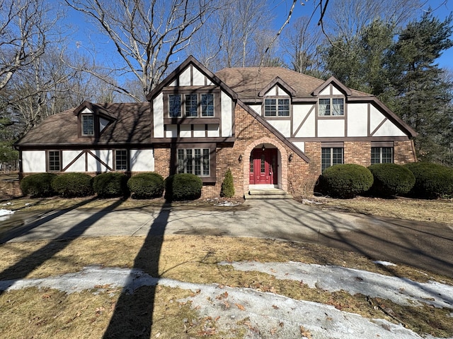 tudor home with brick siding, stucco siding, and a shingled roof