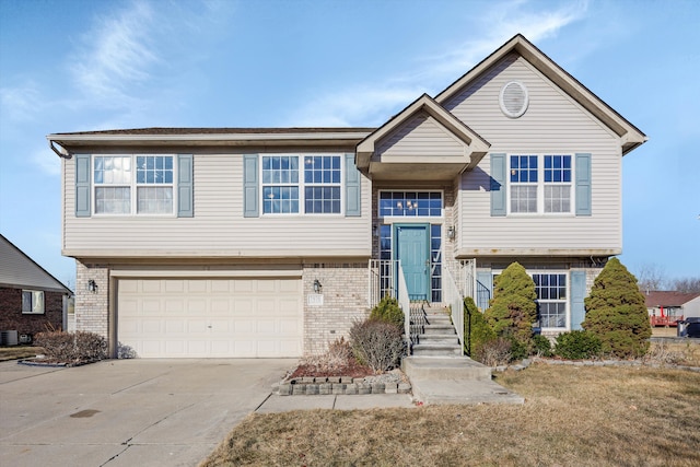 raised ranch with brick siding, concrete driveway, and a garage