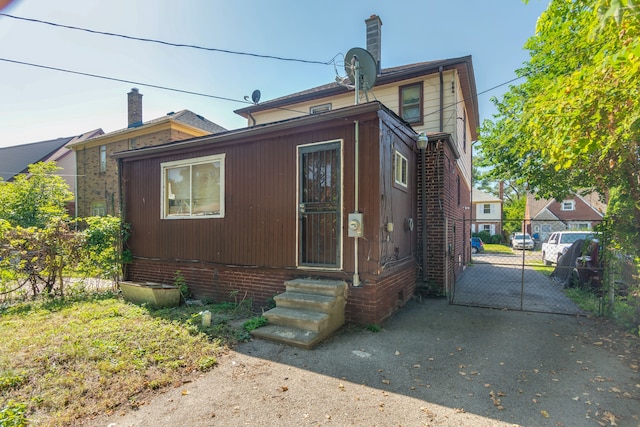 view of front facade featuring a gate, fence, brick siding, and a chimney