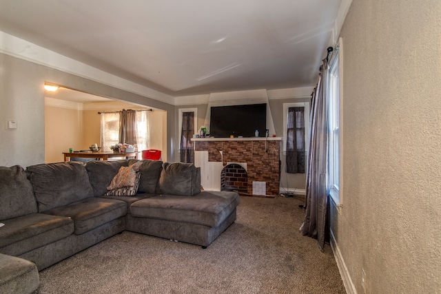 carpeted living room featuring a brick fireplace, a textured wall, and baseboards