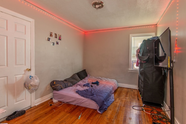 bedroom with baseboards, wood-type flooring, and a textured ceiling