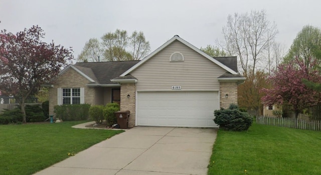 ranch-style home with brick siding, driveway, an attached garage, and a front lawn