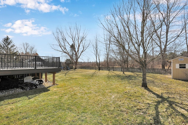 view of yard featuring a shed, a wooden deck, an outdoor structure, and fence