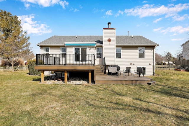 rear view of house featuring fence, a yard, roof with shingles, a wooden deck, and a chimney