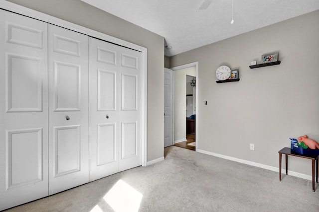 carpeted bedroom featuring a closet, baseboards, and ceiling fan