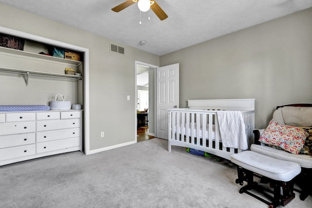 bedroom with baseboards, visible vents, ceiling fan, a nursery area, and carpet flooring