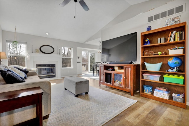 living room with visible vents, a fireplace with flush hearth, wood finished floors, ceiling fan, and vaulted ceiling