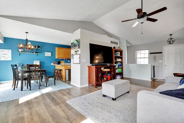 living room featuring visible vents, baseboards, light wood-style flooring, and vaulted ceiling