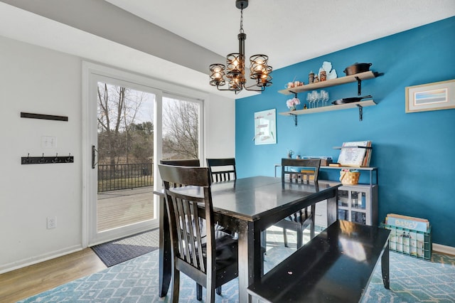 dining area with baseboards, an inviting chandelier, and wood finished floors