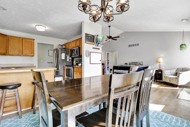 dining space featuring visible vents, lofted ceiling, wood finished floors, and ceiling fan with notable chandelier