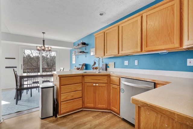 kitchen with a peninsula, a sink, light countertops, light wood-style floors, and dishwasher