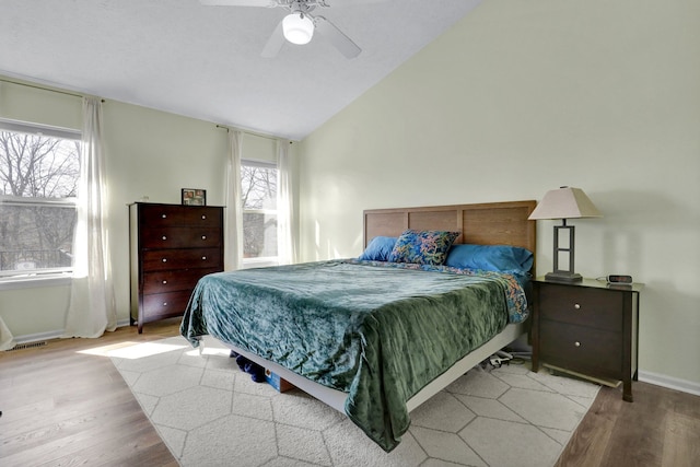 bedroom with a ceiling fan, lofted ceiling, multiple windows, and wood finished floors