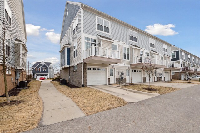 townhome / multi-family property featuring central air condition unit, brick siding, a garage, and concrete driveway