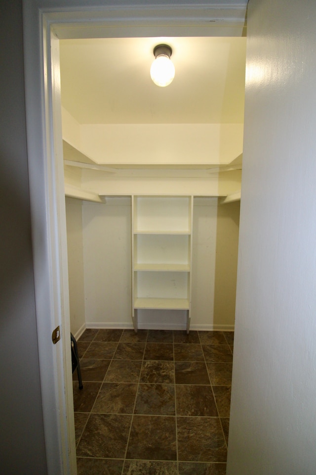 walk in closet featuring stone finish flooring