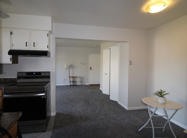 kitchen with under cabinet range hood, dark colored carpet, range with electric stovetop, and dark countertops