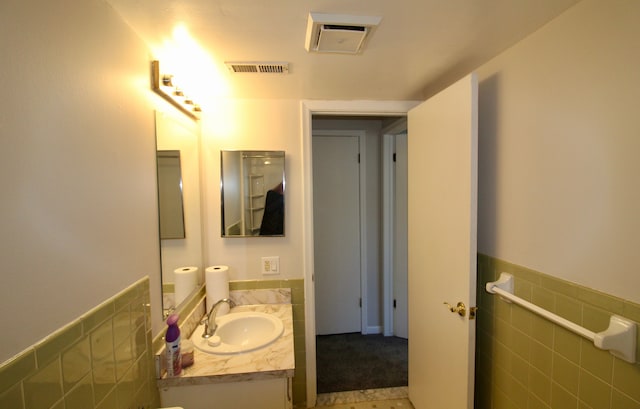 bathroom featuring visible vents, tile walls, a wainscoted wall, and vanity