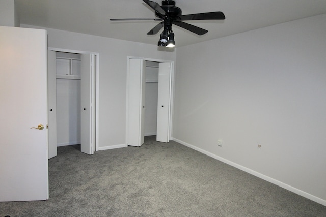 unfurnished bedroom with two closets, baseboards, and carpet floors