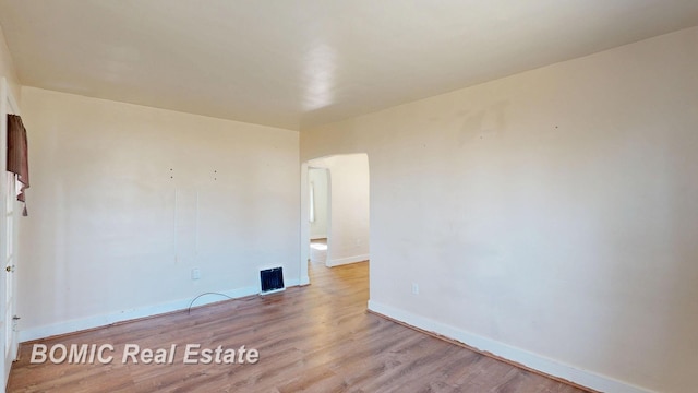 spare room featuring visible vents, baseboards, and wood finished floors