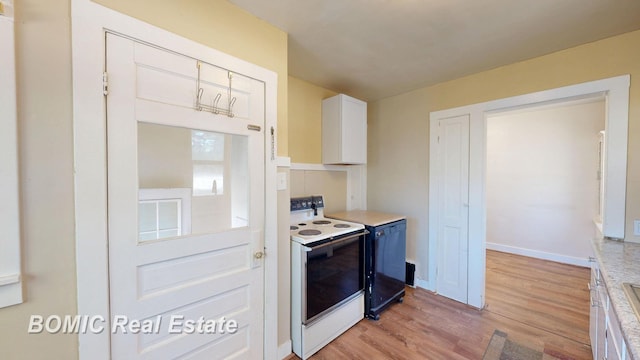 kitchen with electric stove, light wood-style floors, white cabinets, light countertops, and baseboards