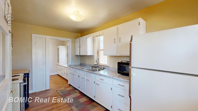 kitchen with white appliances, white cabinets, light countertops, and a sink