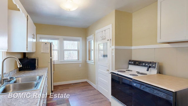 kitchen with black appliances, a sink, light wood-style floors, white cabinets, and light countertops